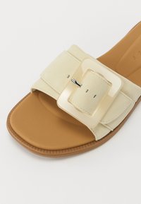 Kremfarget semsket skinn sandaler med bred stropp og stor firkantet lys spenne. Teksturet såle med en brun gummisåle.