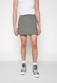 Gonna grigia al ginocchio con vestibilità comoda. Presenta un design semplice e una trama di tessuto. Abbinata a sneakers con fantasia e calzini bianchi.