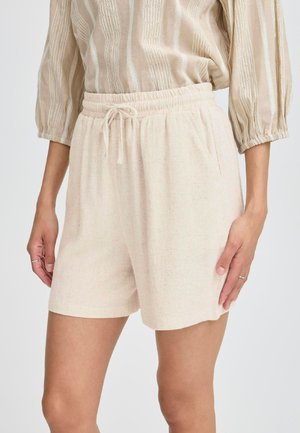 Shorts beige clair en tissu texturé, avec une taille élastique dotée d'un cordon de serrage et des poches latérales.
