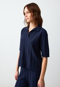 Polo a maniche corte blu navy con un motivo testurizzato e colletto, realizzato in un morbido tessuto knitted.