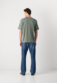 Grøn bomulds t-shirt med korte ærmer, rund hals og en glat tekstur, parret med lyseblå vide denimjeans.