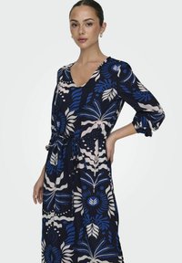 Navy Kleid mit V-Ausschnitt, 3/4-Ärmeln und bindbarem Taillenband. Es hat ein florales Muster in Blau, Weiß und Rosa. Aus weichem, leichtem Stoff gefertigt.