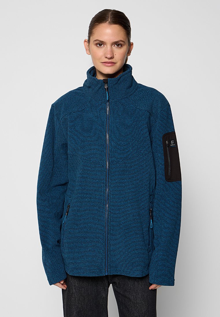 Chaqueta azul texturizada con cremallera y alto cuello, bolsillos laterales y un bolsillo de acento negro en la manga izquierda. Diseñada para uso al aire libre.