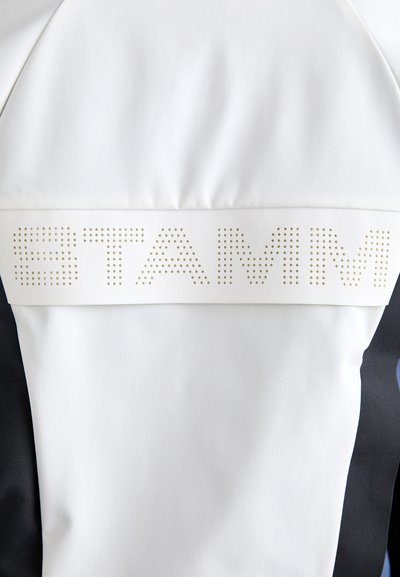Textil alb cu o textură netedă prezintă un logo „STAMM” reliefat și perforat. Accentele de stofă neagră sunt vizibile pe laterale.