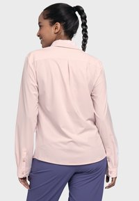 Helles rosa Langarmhemd mit Kragen, ausgestattet mit einem Rückenschlitz und geknöpften Manschetten, kombiniert mit lila Hosen. Glatte Stofftextur.