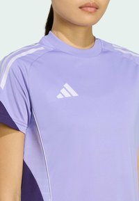 Light purple athletic t-shirt with short sleeves, featuring white stripes on the shoulders and an Adidas logo on the chest. Smooth texture.