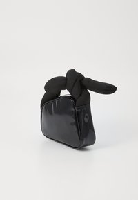 Saco de mão de pele sintética preta com um cabo de tecido atado, apresentando uma forma retangular e uma textura lisa e brilhante.