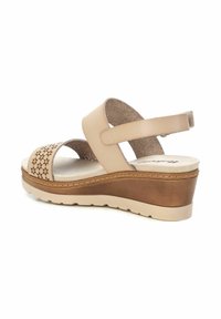 Sandalía de cuña beige con un diseño floral perforado. Cuenta con correas ajustables y una plantilla acolchada. La suela de goma proporciona tracción.