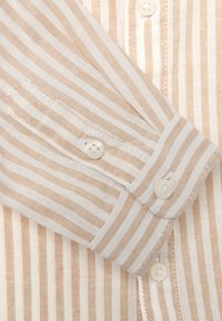 Beige en wit gestreept shirt van een zachte, textuurstof met knoopsluiting en gedetailleerde stiksels langs de manchetten en de sluiting.
