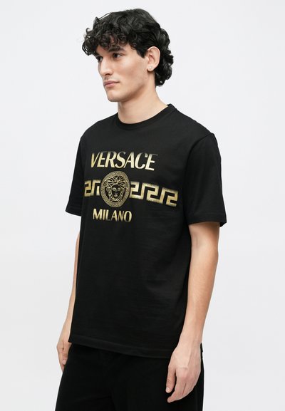 Černé tričko s krátkými rukávy se zlatým potiskem "VERSACE" a "MILANO", zdobené logem Medusa a motivem řeckého klíče. Hladká textura.