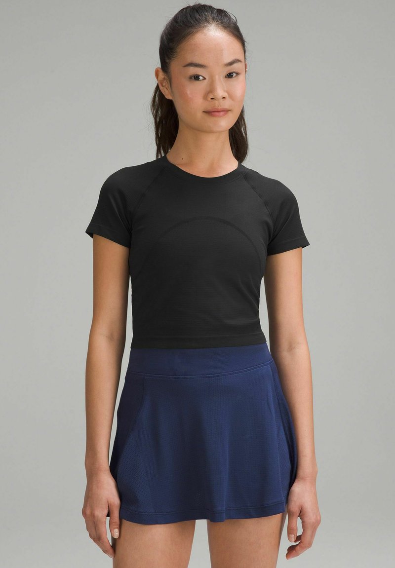 Zwart cropped sport t-shirt met korte mouwen, gecombineerd met een blauwe gemêleerde rok, voorzien van een tailleband en een comfortabele pasvorm.