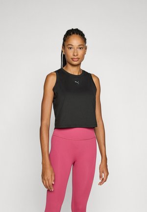 Black sleeveless crop top with a round neckline and Puma logo. Worn with fitted, high-waisted pink leggings, displaying a smooth texture.