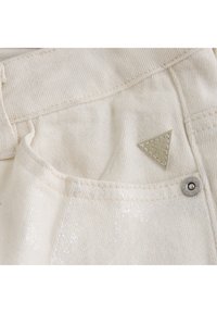 Krämfärgad denimtyg med en subtil lyster, som har en triangulär strukturerad logopatch och en metallknapp som accent på fickan.