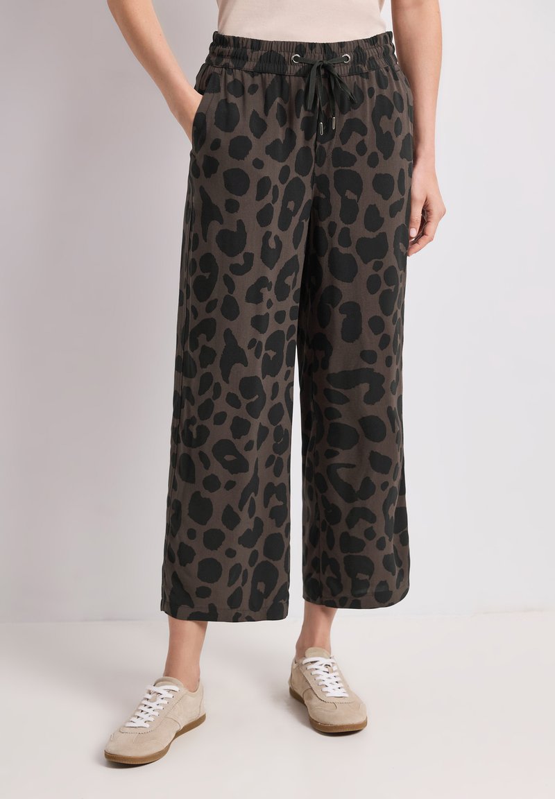 Pantalones cropped de pierna ancha con estampado de leopardo en marrón oscuro y negro, cintura elástica con cordón, combinados con zapatillas beige.