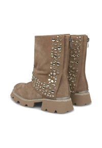 Bottines en suède marron avec une finition texturée, ornées de grands clous métalliques sur les côtés et d'une semelle en caoutchouc épaisse avec un accent argenté.