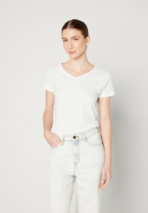 T-shirt blanc à col en V avec des manches courtes, texture lisse et design ajusté, associé à un jean en denim léger taille haute.