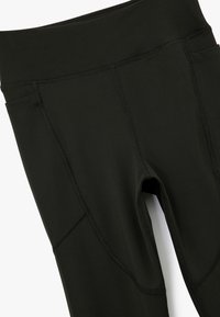 Svarta atletiska leggings gjorda av stretchigt tyg, med hög midja, flatlock-sömmar och sidofickor. Mjuk textur, figursydd design.