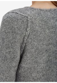 Šedý pletený svetr s texturovaným a měkkým, chlupatým vzhledem. Má zaoblený výstřih a viditelné švy na ramenou.