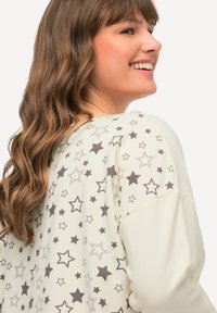 Lichtcrème sweatshirt met een sterrenpatroon in donkergrijs, met raglanmouwen en een zachte textuur. Accentueert met geribde manchetten.