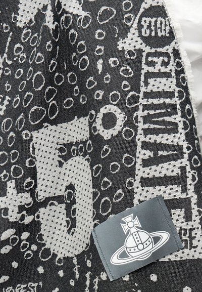 Ύφασμα ασπρόμαυρο με αφηρημένους κύκλους, αποσπασματικό κείμενο και γκρίζο σημείο με στυλιζαρισμένο πλανήτη με δαχτυλίδι και σύμβολο σταυρού.