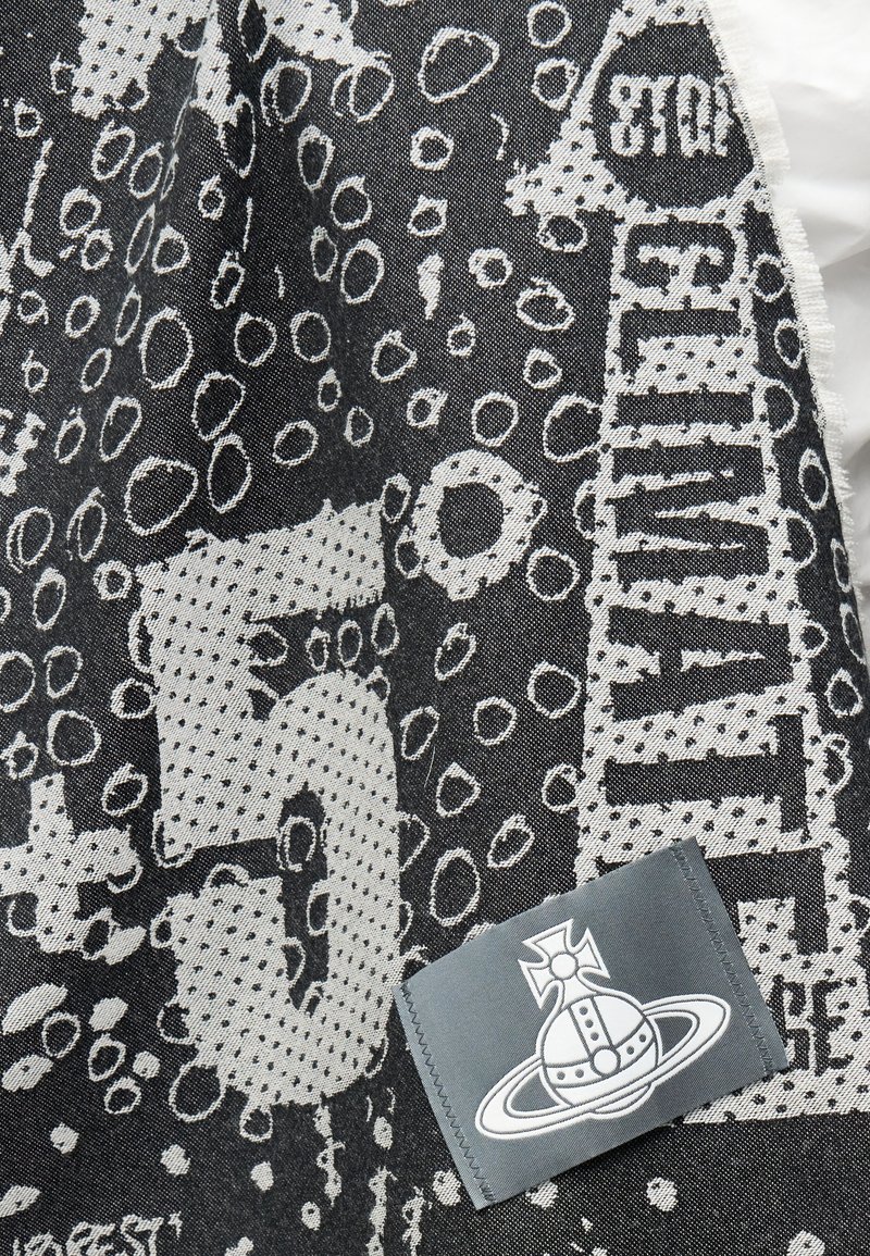 Tissu à motifs noir et blanc avec des cercles abstraits, du texte fragmenté et une partie grise avec une planète stylisée avec un anneau et un symbole de croix.