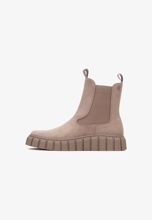 Bottine Chelsea en daim taupe avec des languettes, des panneaux latéraux élastiques et une semelle épaisse à crampons.