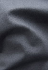 Tkanina w ciemnoszarym kolorze o gładkiej fakturze, z delikatnymi zagnieceniami i lekkim, tkanym wyglądem. Brak widocznych wzorów czy zdobień.