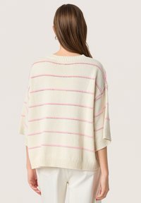 Crème breiclijf met roze strepen, met een losse pasvorm, korte mouwen, geribbelde zoom en oogjesdetails door het hele ontwerp.