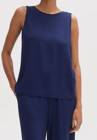 Granatowa bezrękawnik z gładkiego materiału, z okrągłym dekoltem i luźnym krojem, zestawiony z pasującymi luźnymi spodniami.