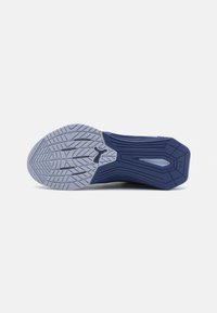 Semelle d'une chaussure de sport avec un fond en caoutchouc texturé de couleur gris, muni de rainures, et une partie supérieure de couleur bleu foncé, conçue pour l'adhérence et le soutien.