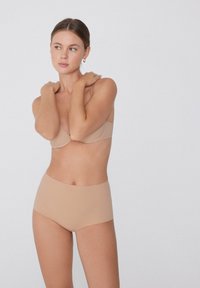 Beżowy biustonosz bezszwowy z fiszbinami i regulowanymi ramiączkami, w zestawie z wysokim beżowym majtkami. Gładka tekstura, minimalistyczny design.