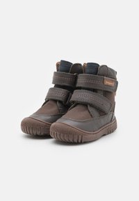 Bottines en cuir marron avec deux sangles Velcro, col rembourré, semelle en caoutchouc et accents texturés. Conçues pour le confort et la durabilité.