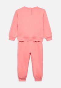 Σετ με ροζ φούτερ και αντίστοιχο παντελόνι φόρμας. Μαλακό ύφασμα, μακριά μανίκια με ελαστικές μανσέτες και ελαστική μέση στο παντελόνι. Λεπτομέρεια με κουμπιά στην πλάτη.