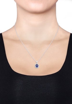 Collier en chaîne en argent avec un pendentif texturé accentué d'argent, portant une pierre précieuse ronde bleu foncé entourée de petites pierres claires.