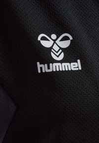 Zwart sportshirt van een textiele stof. Bevat een witte logo van een gestileerde bij boven de merknaam "hummel" in een vetgedrukt lettertype.