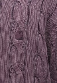 Πλεκτό πο υλόβερ σε μωβ απόχρωση με σχέδια κοτσίδας, υφασμάτινη υφή και μοναδική λεπτομέρεια με κουμπί στο μπροστινό μέρος. Μαλακό και χοντρό υλικό.