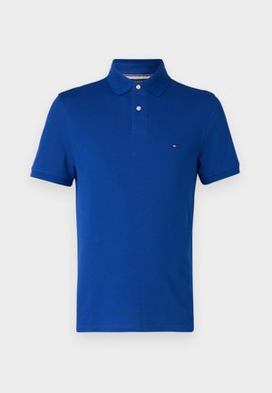 Polo bleu en coton, avec une patte de boutonnage à trois boutons, des manches courtes et un petit logo sur la poitrine gauche.
