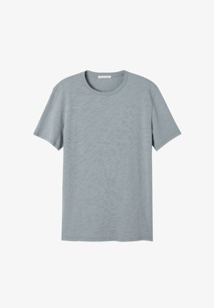 Trumpas rankovėmis apvalios apykaklės marškinėliai, pagaminti iš minkštos, šviesiai mėlynos medžiagos su subtilia tekstūrine raštu ir nebaigtu apvadu.