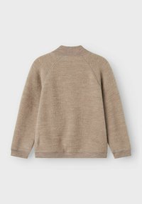 Beige tröja med ribbad krage och muddar, tillverkad av mjukt tyg. Har raglanärmar och en rak fåll i botten.