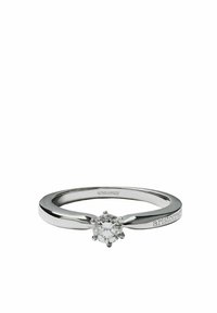 Anillo de plata con un acabado pulido que presenta una gema clara redonda. Diseño minimalista con una banda estrecha y el nombre de la marca grabado.