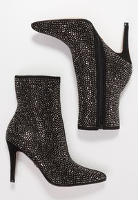 Botines de ante negro con tacones altos, punteras puntiagudas, cremalleras laterales y cubiertos de pequeños clavos de plata.