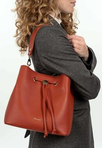 Borsa a secchiello rossa in pelle con finitura texture, tracolla regolabile, chiusura con coulisse e dettagli in metallo dorato.