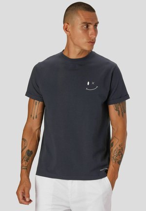 Marineblaue Baumwoll-T-Shirt mit rundem Halsausschnitt, kurzen Ärmeln und einem kleinen weißen Smiley-Gesicht auf der Brust. Sanfte Textur.