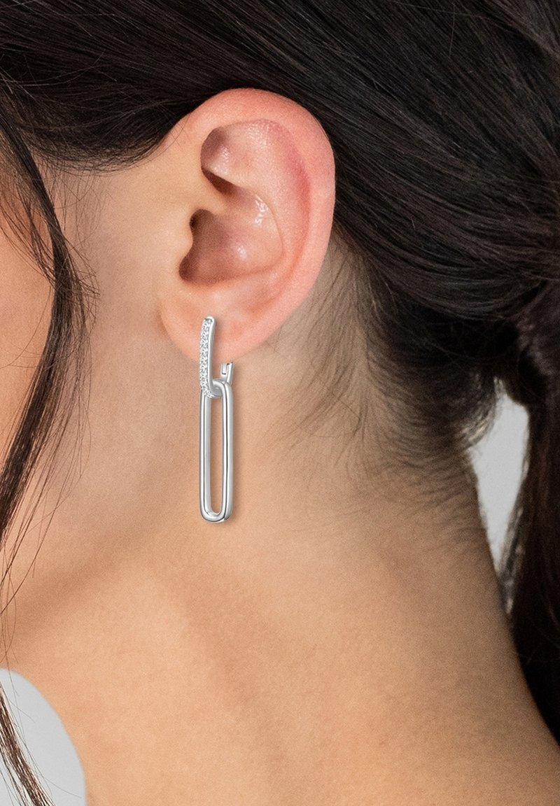 Srebrne uhane v obliki kapljice z elegantnim, podolgovatim oblikovanjem in subtilnim leskom na vrhu. Gladek zaključek, minimalističen stil.