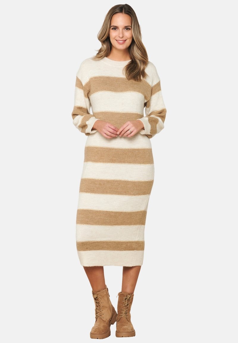 Abito a maglia a righe beige e crema con maniche lunghe, scollatura rotonda e taglio dritto, abbinato a stivali alla caviglia marroni con lacci.