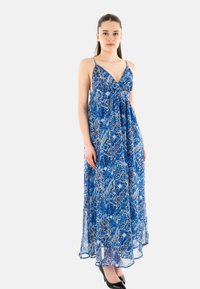 Abito lungo in blu e beige con motivo floreale, realizzato in tessuto leggero con spalline sottili e scollatura a V profonda.