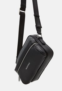 Borsa a tracolla nera in pelle texturizzata, dotata di chiusura con zip argentata, tracolla regolabile e discreto logo.