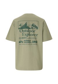 Olivgrünes T-Shirt mit Berggrafik und Text: "Outdoor Explorer", "Whistler", "Das Abenteuer beginnt dort, wo der Weg endet" sowie einer Illustration von Bäumen.