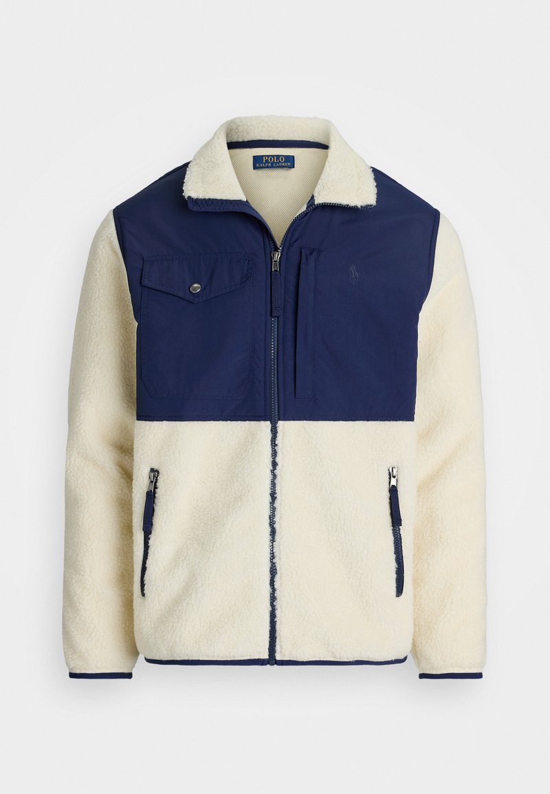 Fleece jacket with a cream body and navy blue nylon upper. Features a zip front, two side pockets, and a chest pocket with button closure.