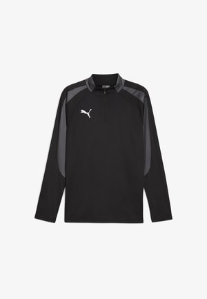 Tricou sportiv negru cu mânecă lungă și fermoar la jumătate, având accente gri pe umeri și un logo alb pe piept. Textura țesăturii este netedă.